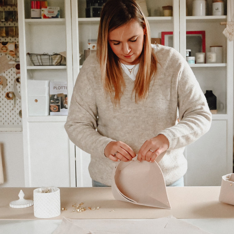 Jana Köter von Fabulous Plotterlove steht an einem Tisch und bastelt einen Korb für Nikolaus aus Filz und goldenen Heftklammern